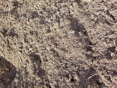 Brown, coarse soil texture with various organic materials.