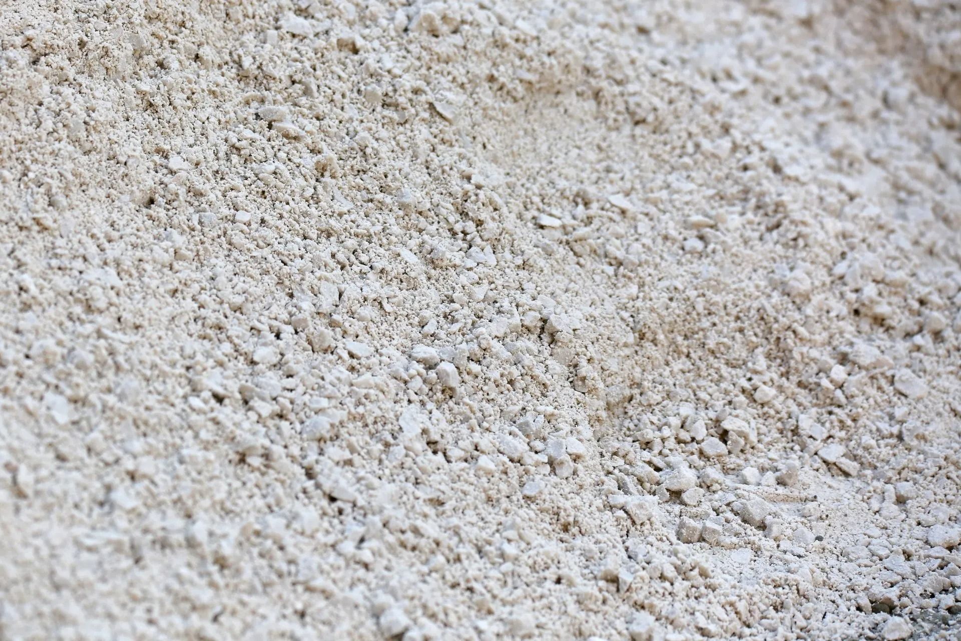 Pile of light-colored, granular material with a slightly uneven surface.