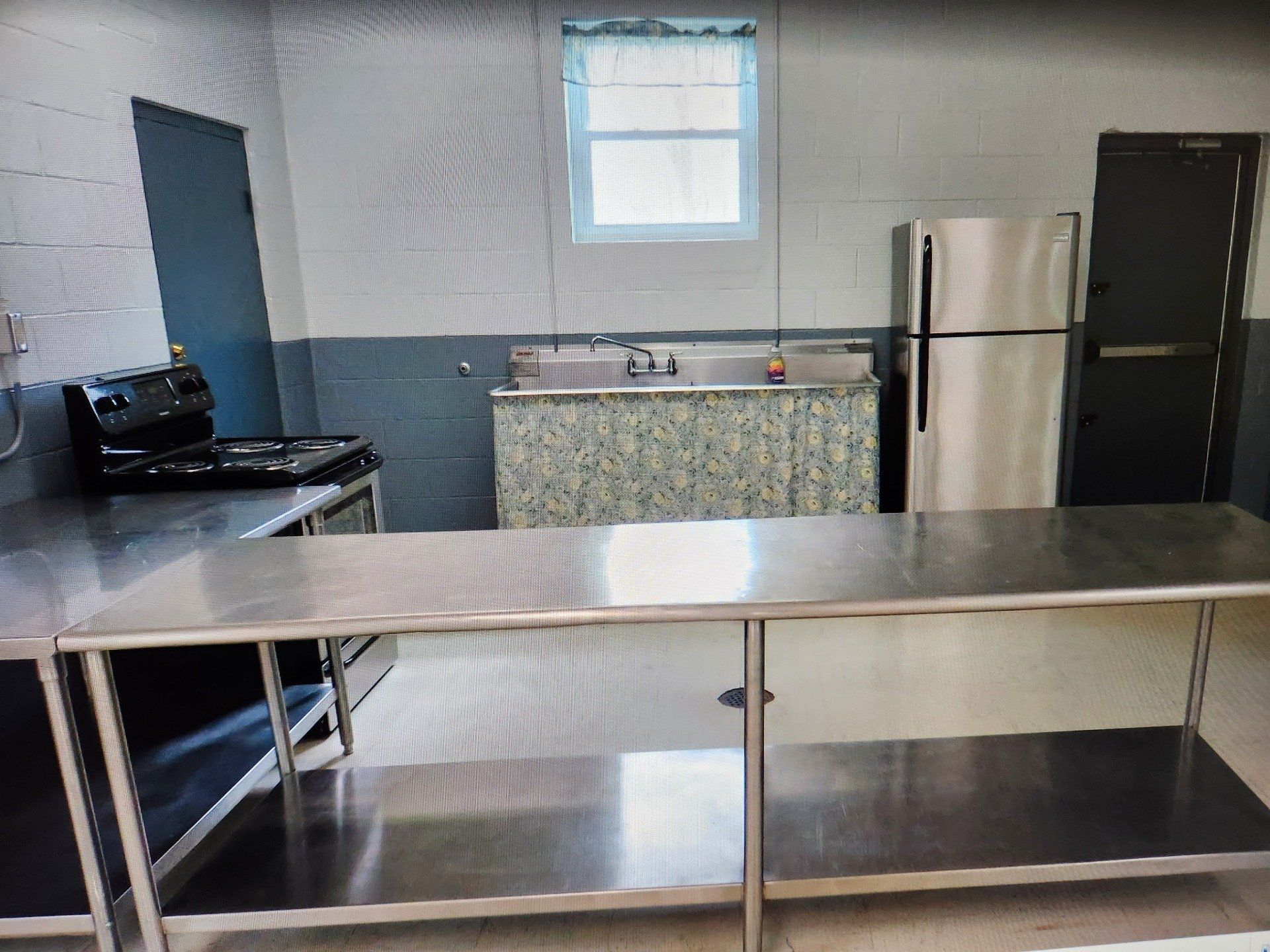 A kitchen with a stainless steel table and a refrigerator