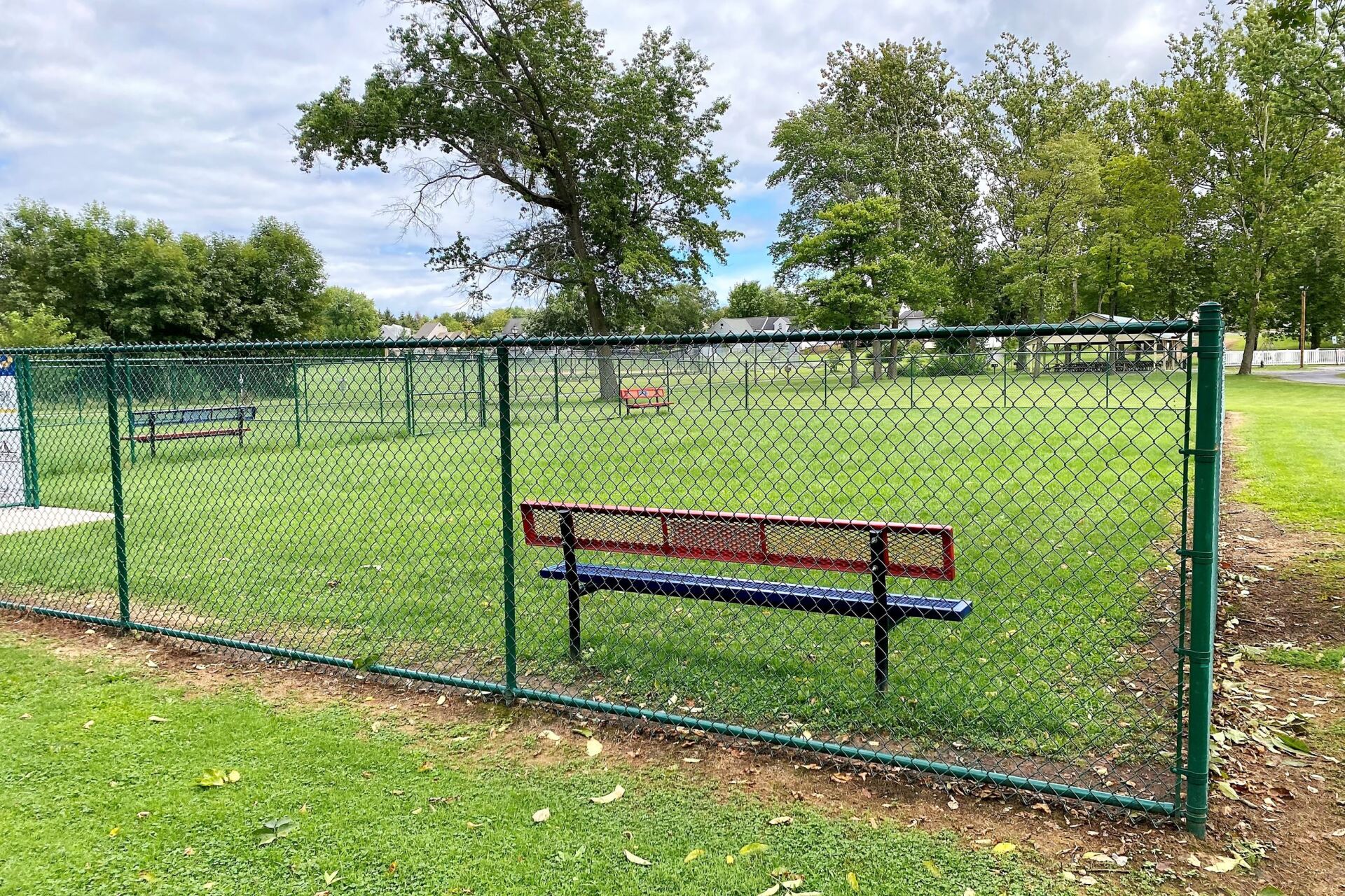 A park with a chain link fence and a bench