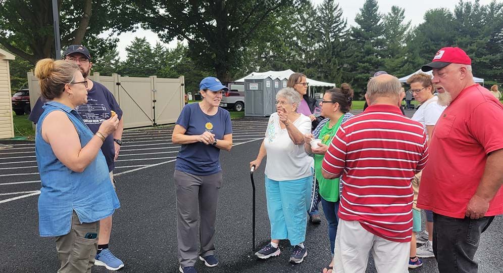 A group of people are standing in a parking lot talking to each other.