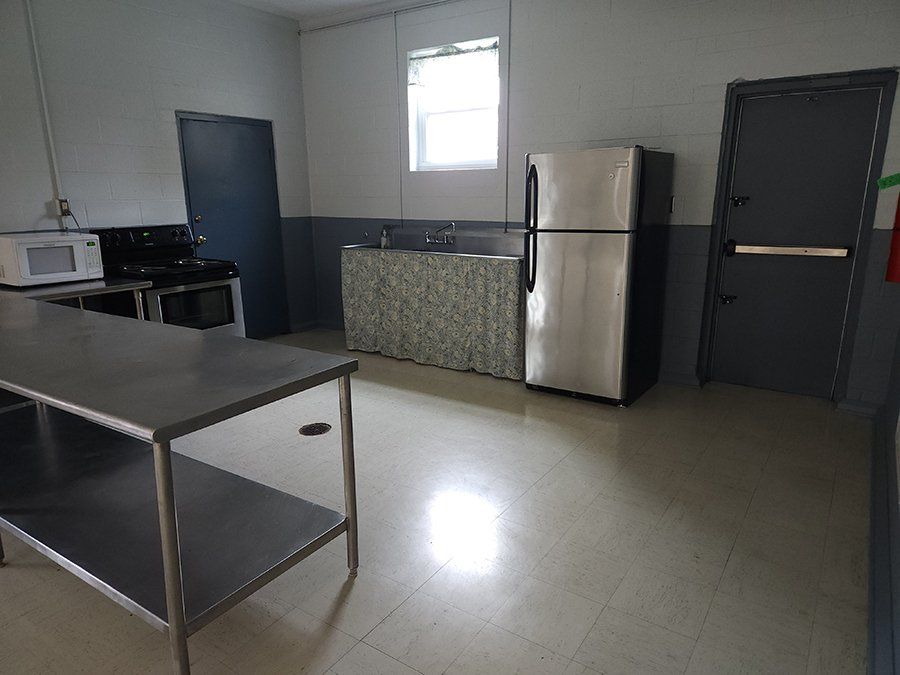 A kitchen with a stainless steel table and a refrigerator