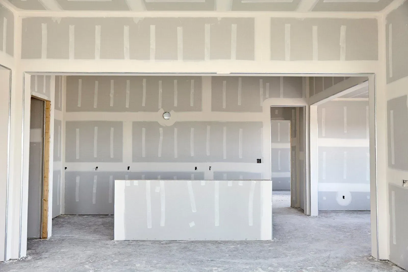 Unfinished kitchen with drywall, a central island, and open doorways in a new home.