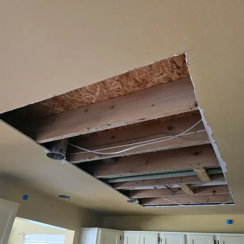 Kitchen ceiling cut open, exposing wooden joists and wiring during renovation