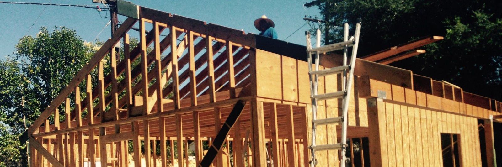 Wood-framed custom home under construction showing structural framing and roof sheathing.