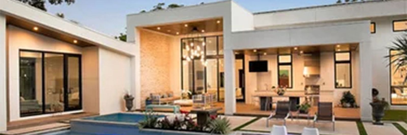 Modern Los Angeles custom home at dusk with pool, glass walls and covered outdoor living.