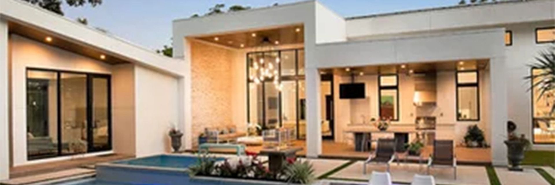 Modern Los Angeles custom home at dusk with pool, glass walls and covered outdoor living.