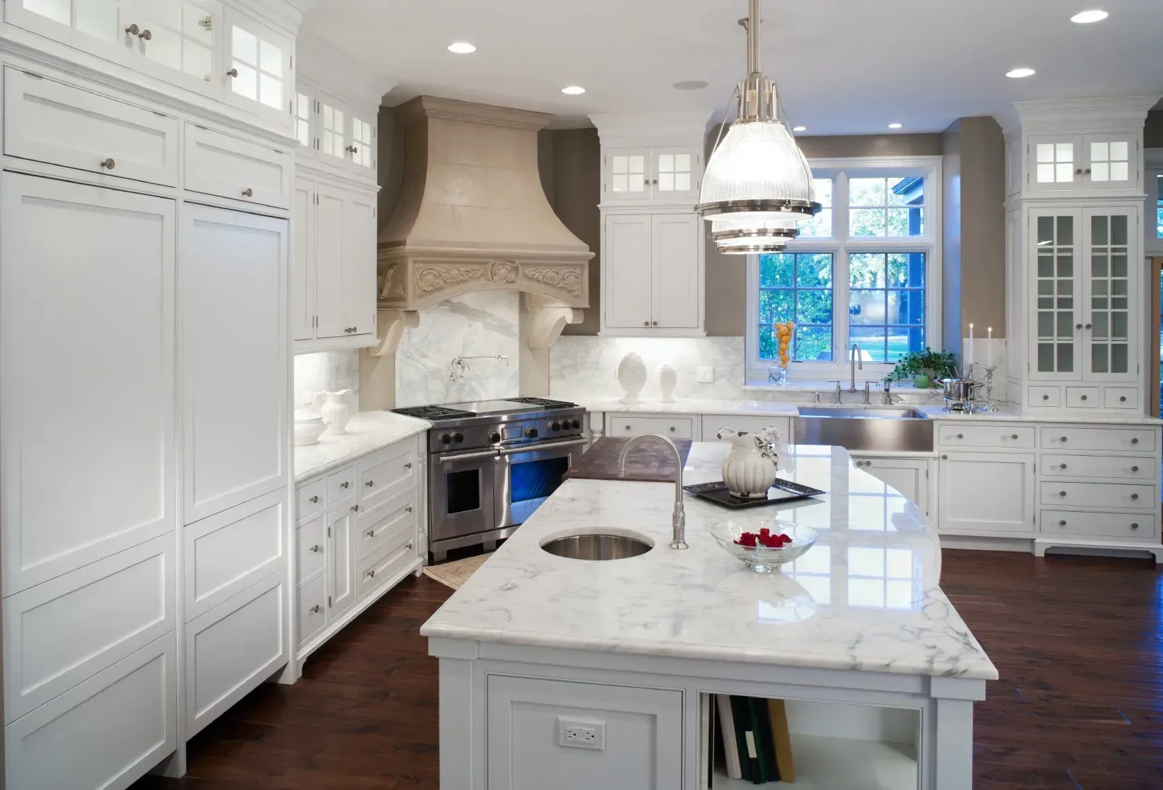A kitchen with white cabinets and marble counter tops
