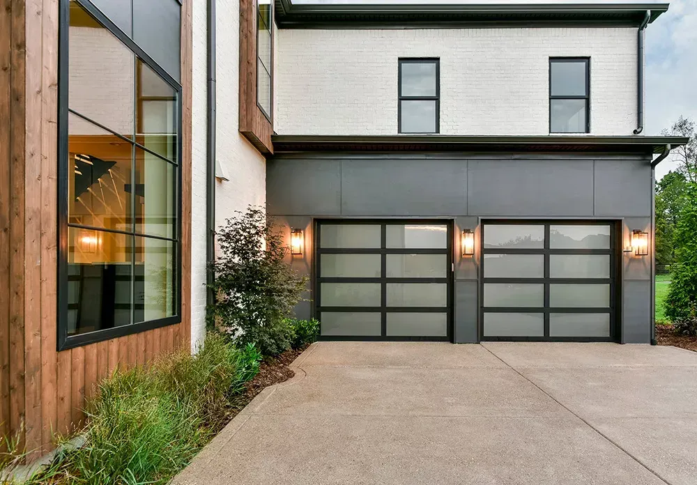 A modern house with a large garage door and a lot of windows.