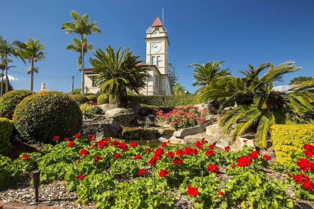 A Clock Tower is Surrounded by Flowers and Palm Trees in a Park — Nicks Readymix in Imbil, QLD