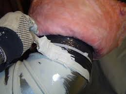 A person is painting a pipe with a brush.