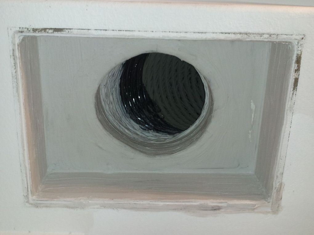 A hole in the ceiling with a hose coming out of it.