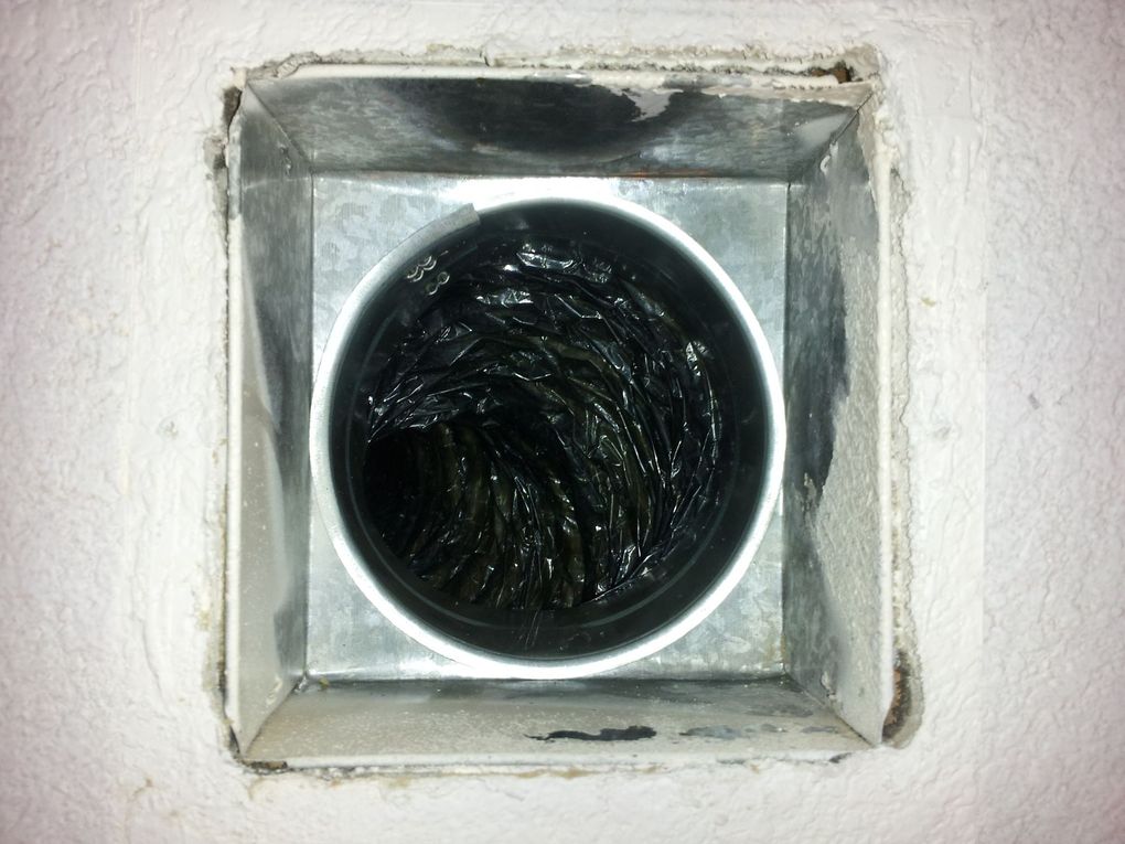 The inside of a metal duct with a black hose coming out of it