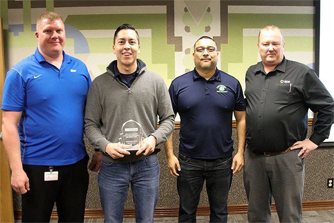 A group of men are standing next to each other and one of them is holding a trophy.