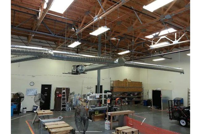 A large warehouse with a lot of pipes hanging from the ceiling