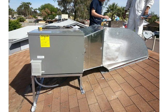 Two men are working on an air conditioner on a roof