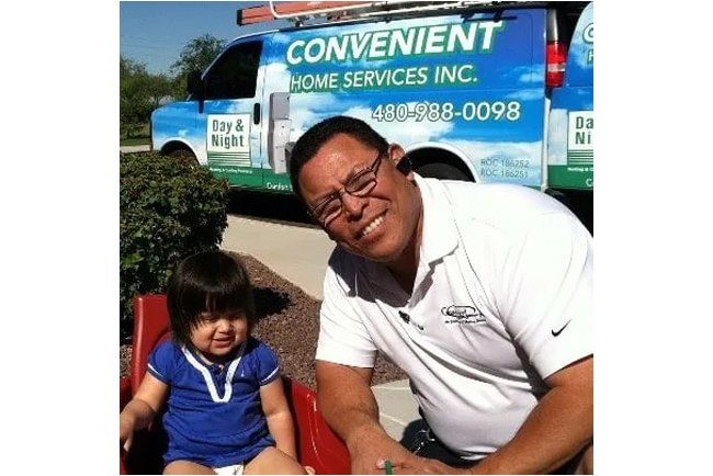 A man sitting next to a little girl in front of a convenient home services inc. truck