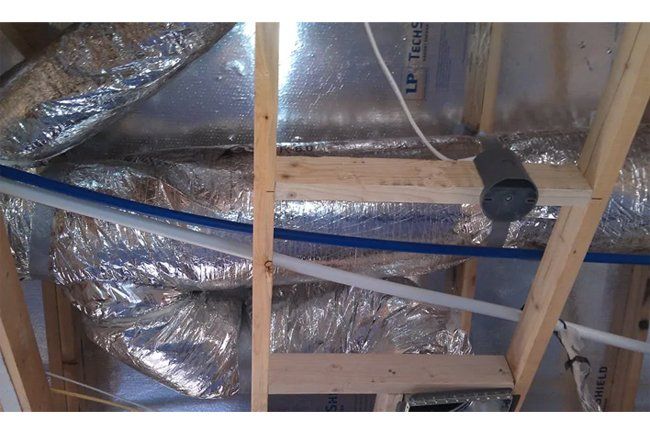 A ceiling with a lot of pipes and aluminum foil on it