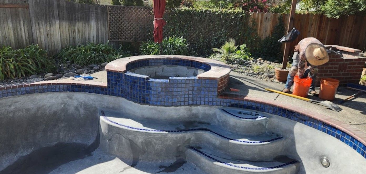 A man is working on a swimming pool in a backyard.