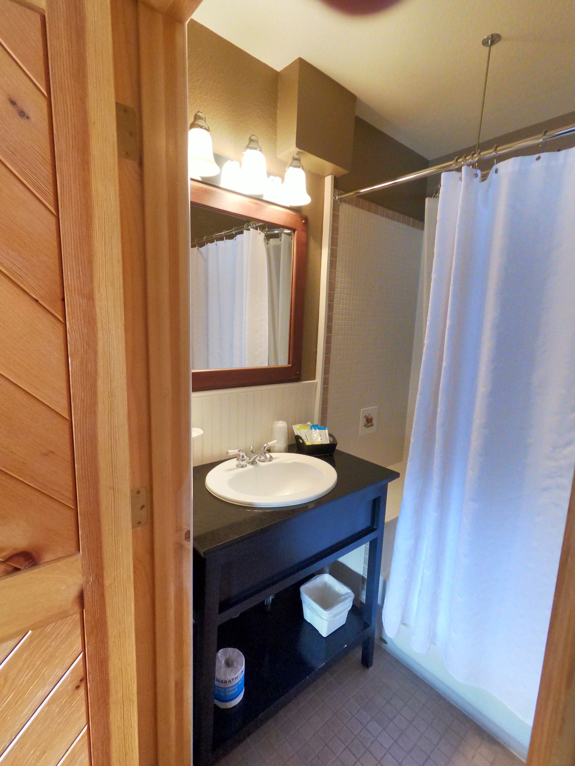 A bathroom with a sink a mirror and a shower curtain