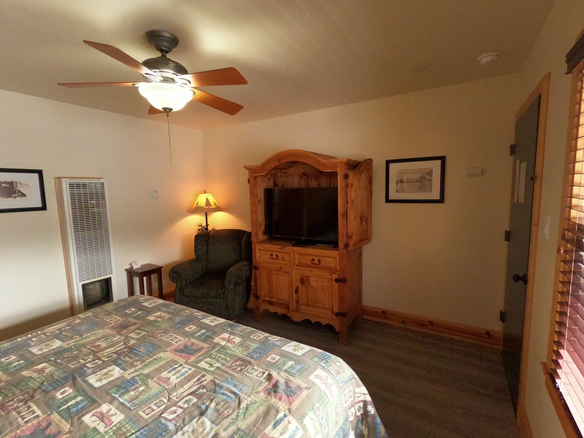 A bedroom with a bed , chair , television and ceiling fan.