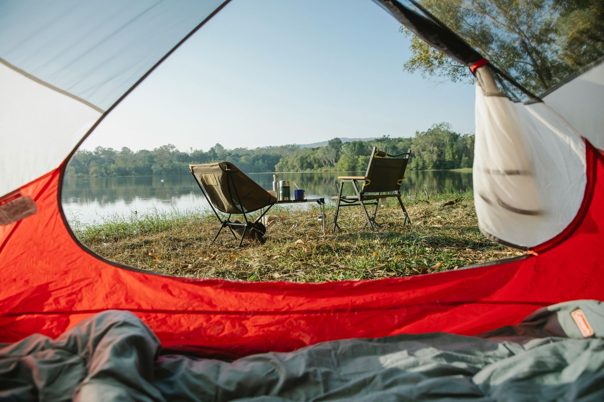 A person is sleeping in a tent with a view of a lake.