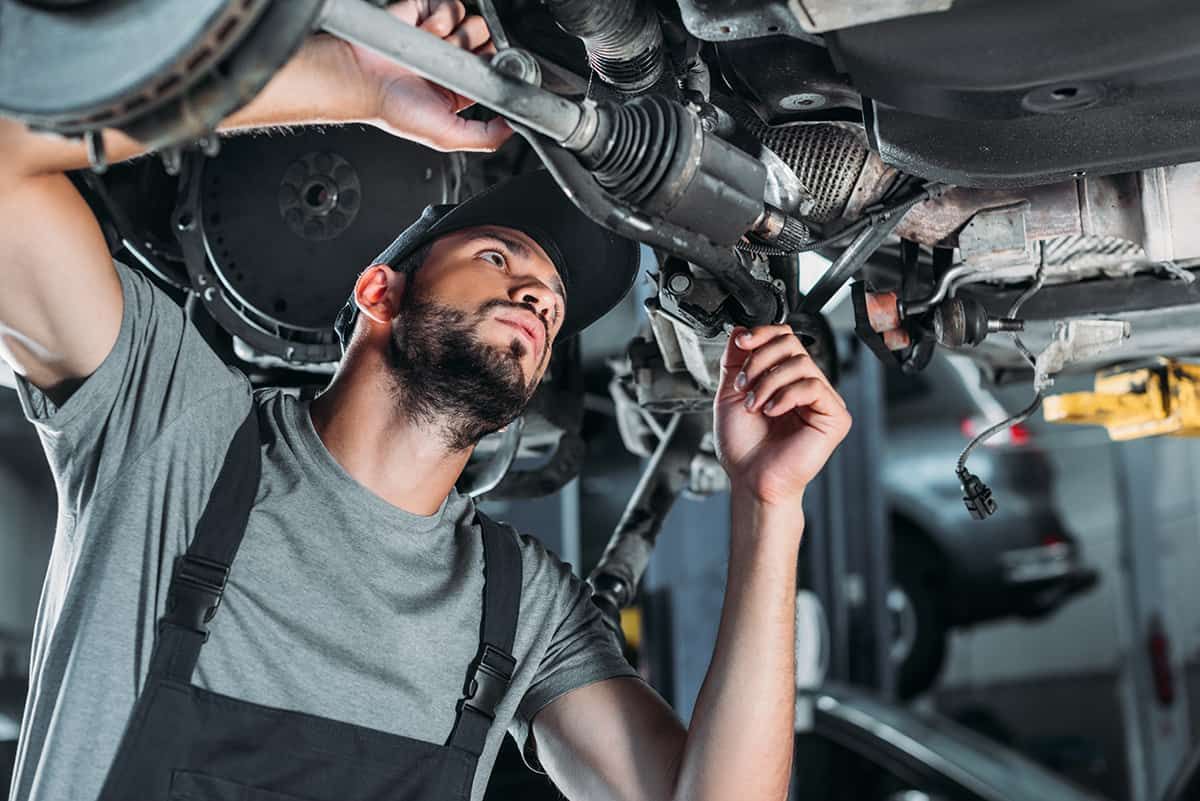 A man is working under a car in a garage.