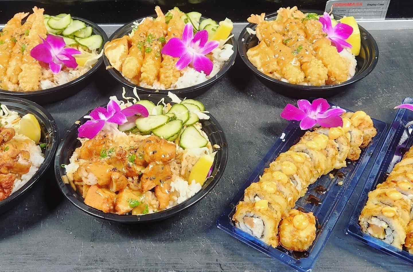 A table topped with bowls of food and plates of sushi.