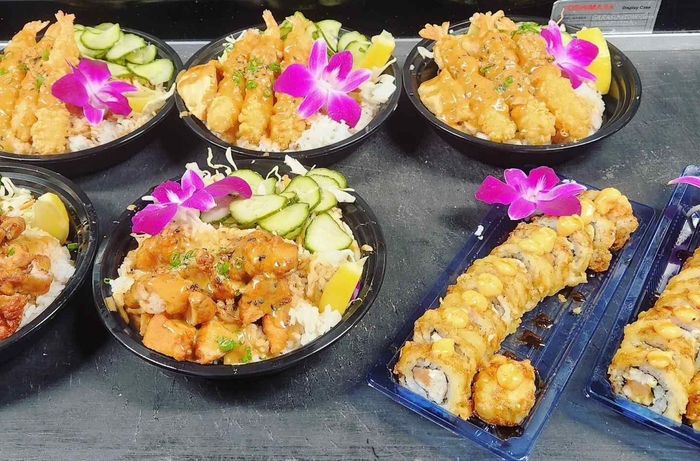 A table topped with bowls of food and plates of sushi.