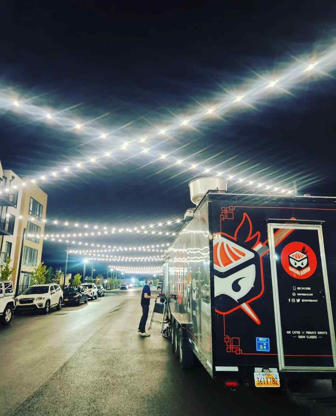 A food truck is parked on the side of the road at night