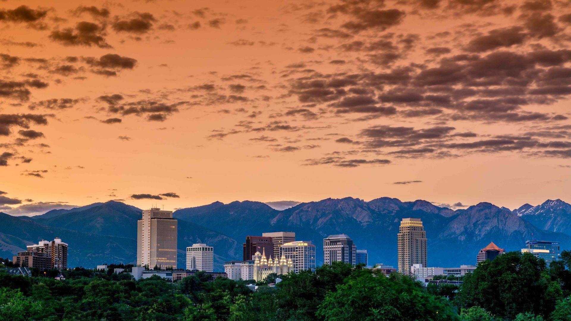 A city skyline with mountains in the background at sunset.