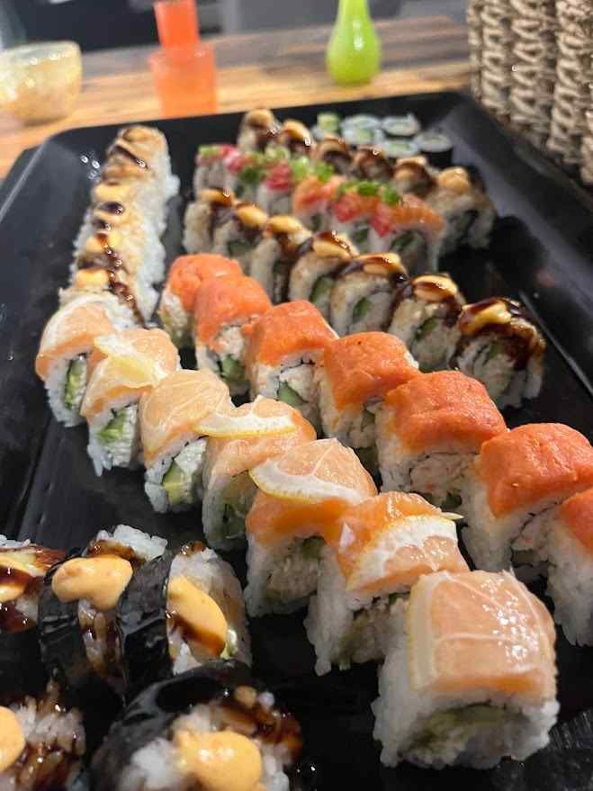 There are many different types of sushi on a black plate.
