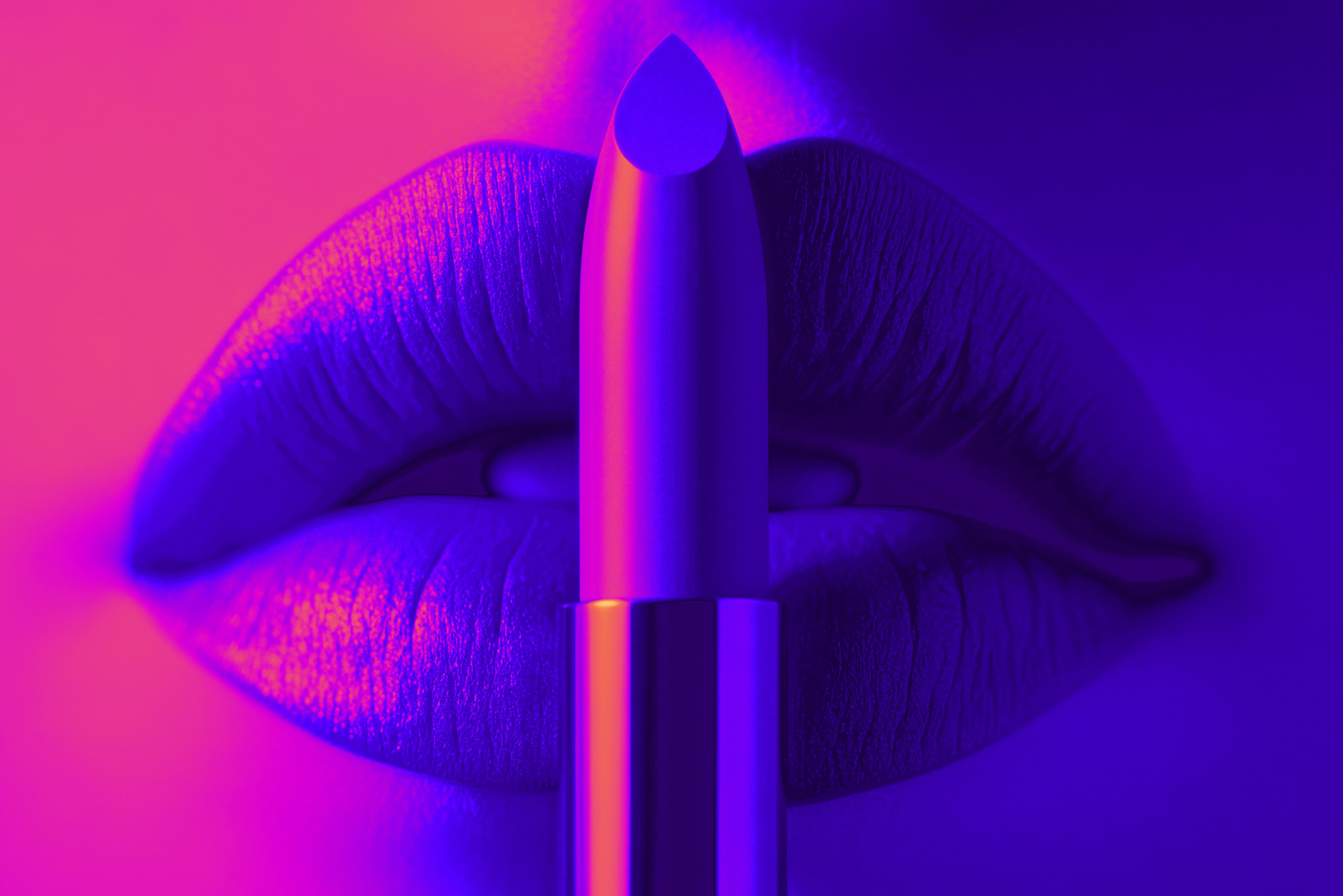 Close-up of lips with a lipstick in front of them, illuminated in pink and blue light.