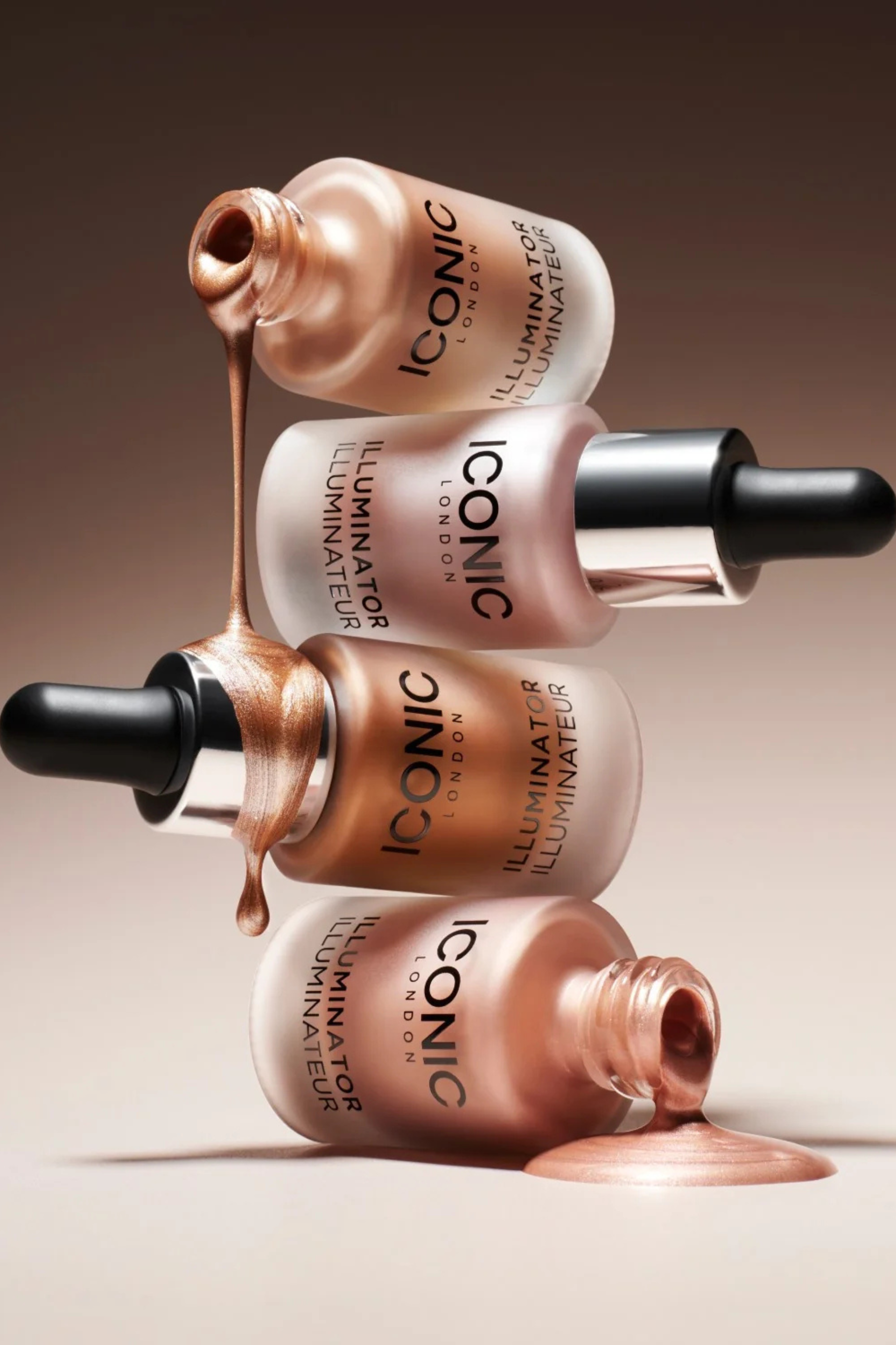 Four bottles of Iconic Illuminator highlighter stacked, dripping product.