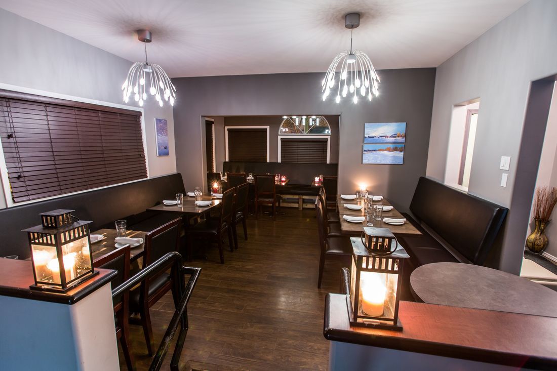 Restaurant interior: dark gray walls, tables set with glassware, decorative lanterns, modern chandeliers.