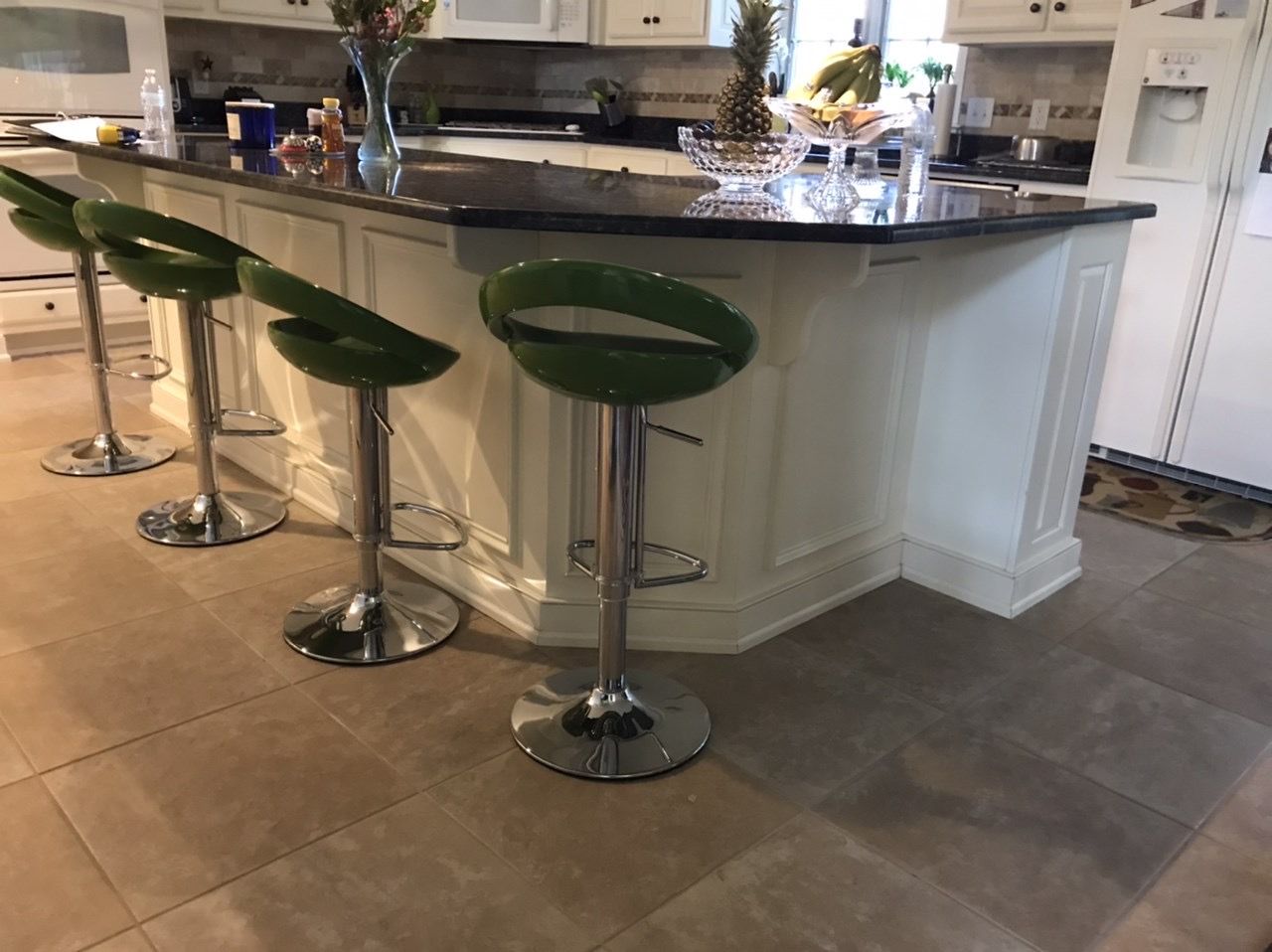 Three green bar stools are sitting in front of a kitchen island.
