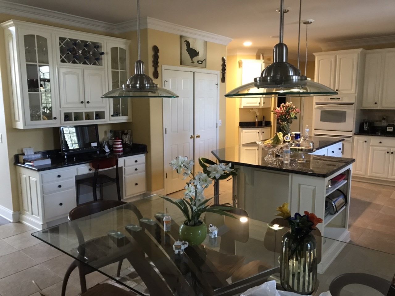 A kitchen with white cabinets and a glass table