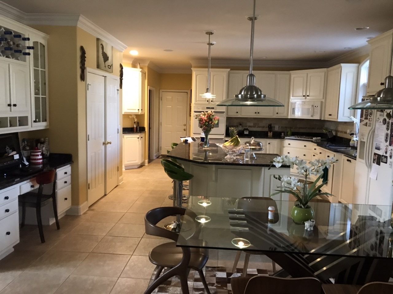 A kitchen with white cabinets and a glass table