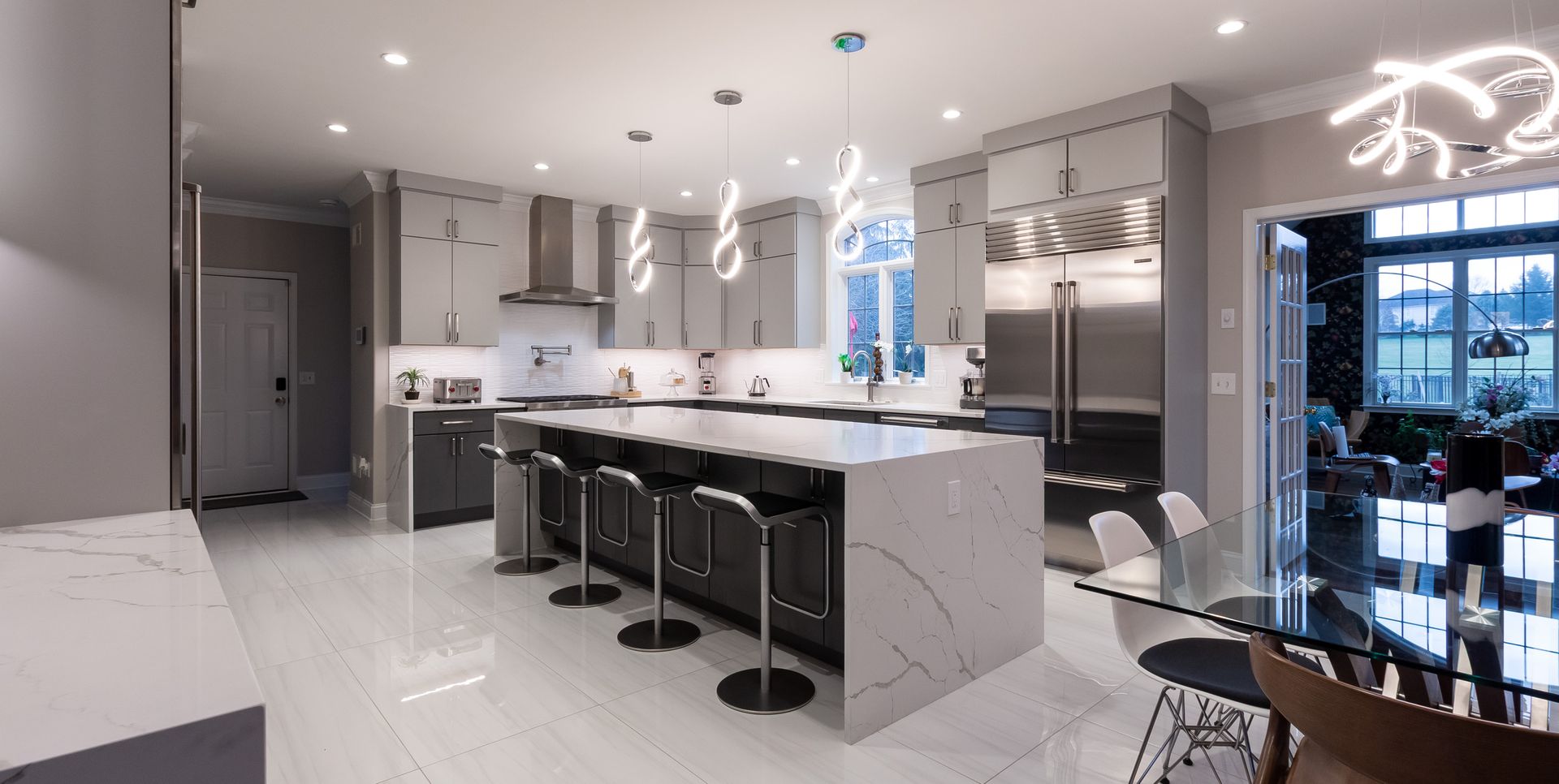 A kitchen with a large island , stools , a refrigerator and a table.
