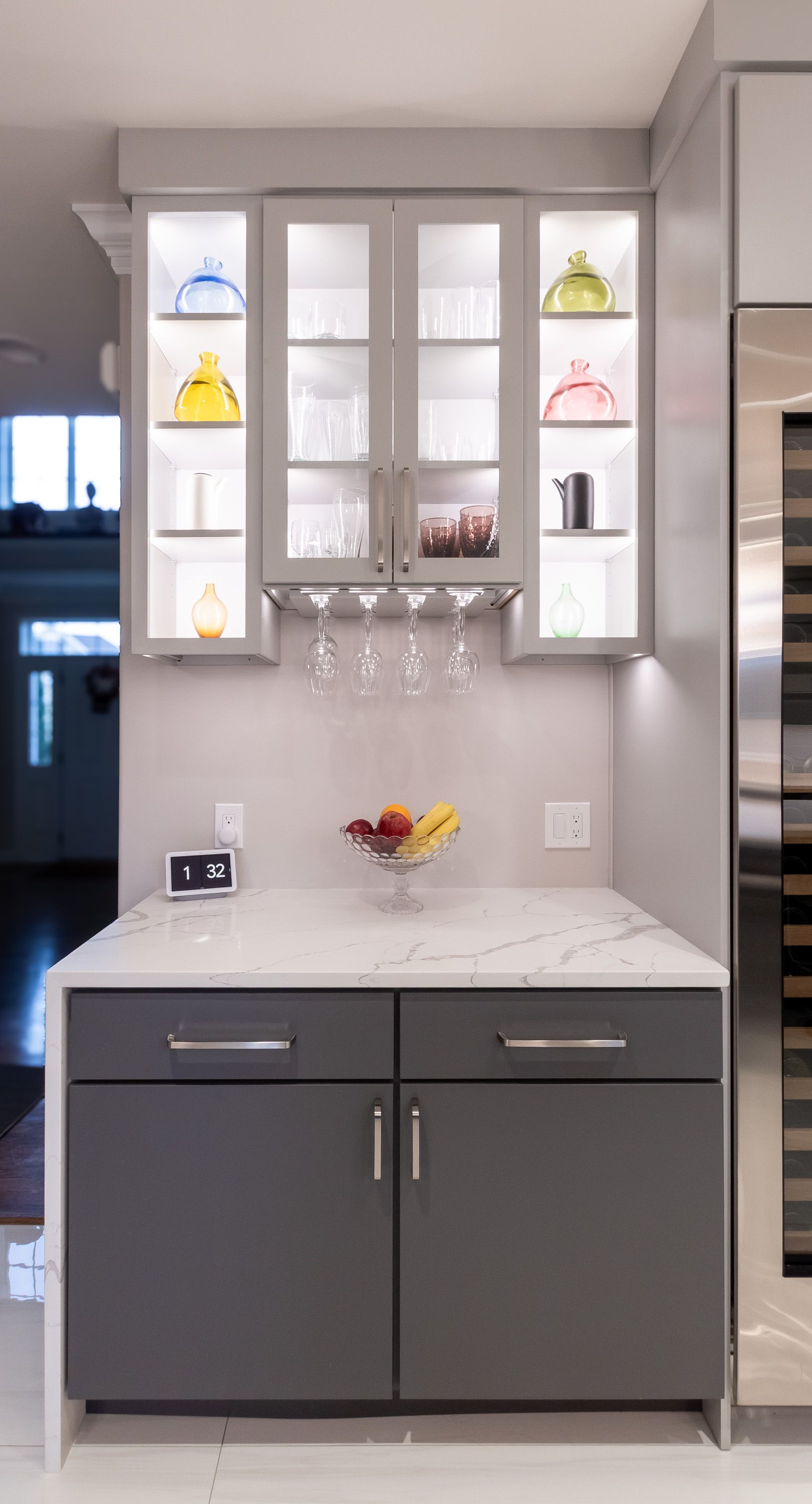 A kitchen with gray cabinets , white counter tops , stainless steel appliances and a wine cooler.