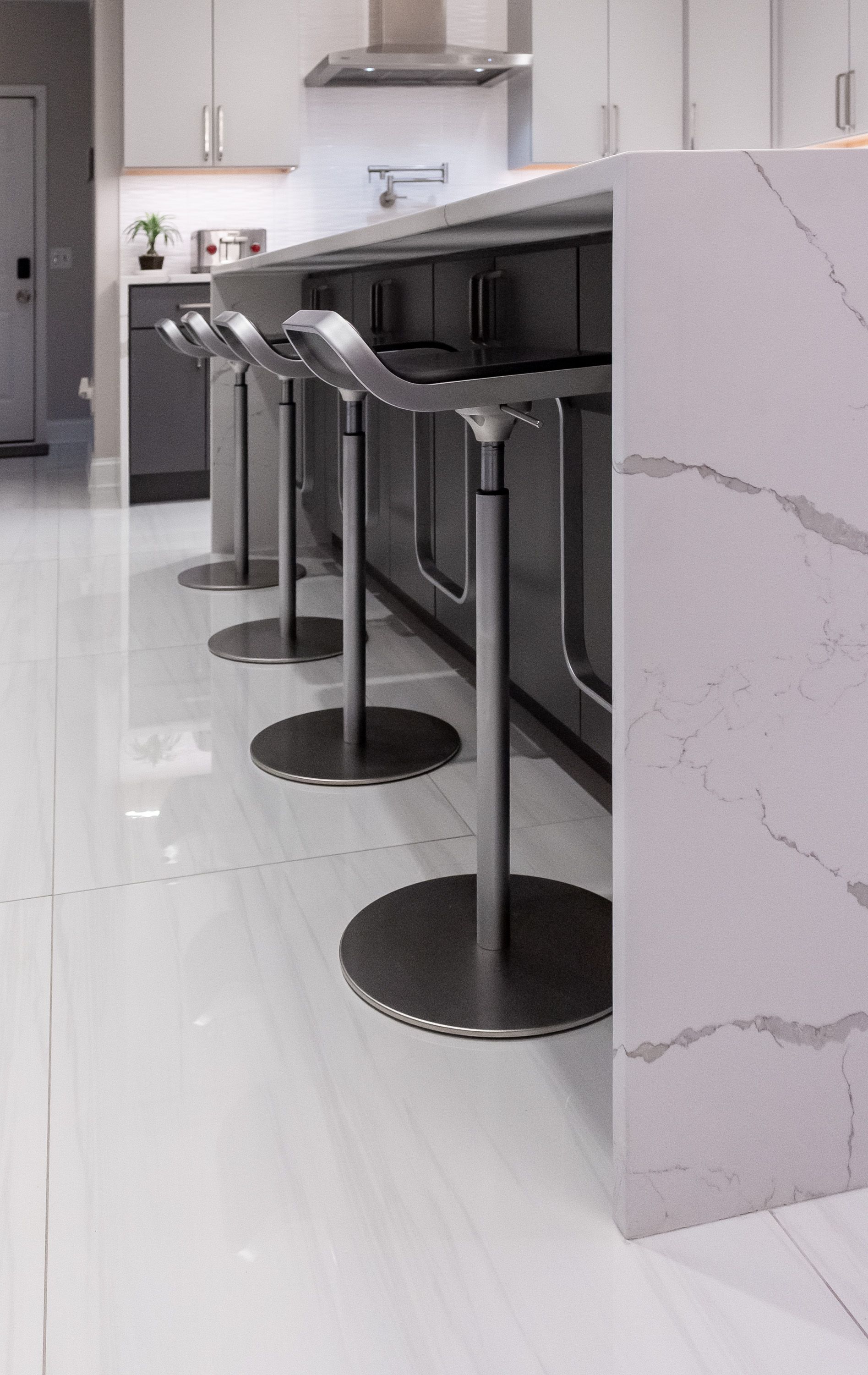 A row of bar stools are lined up next to a white counter in a kitchen.