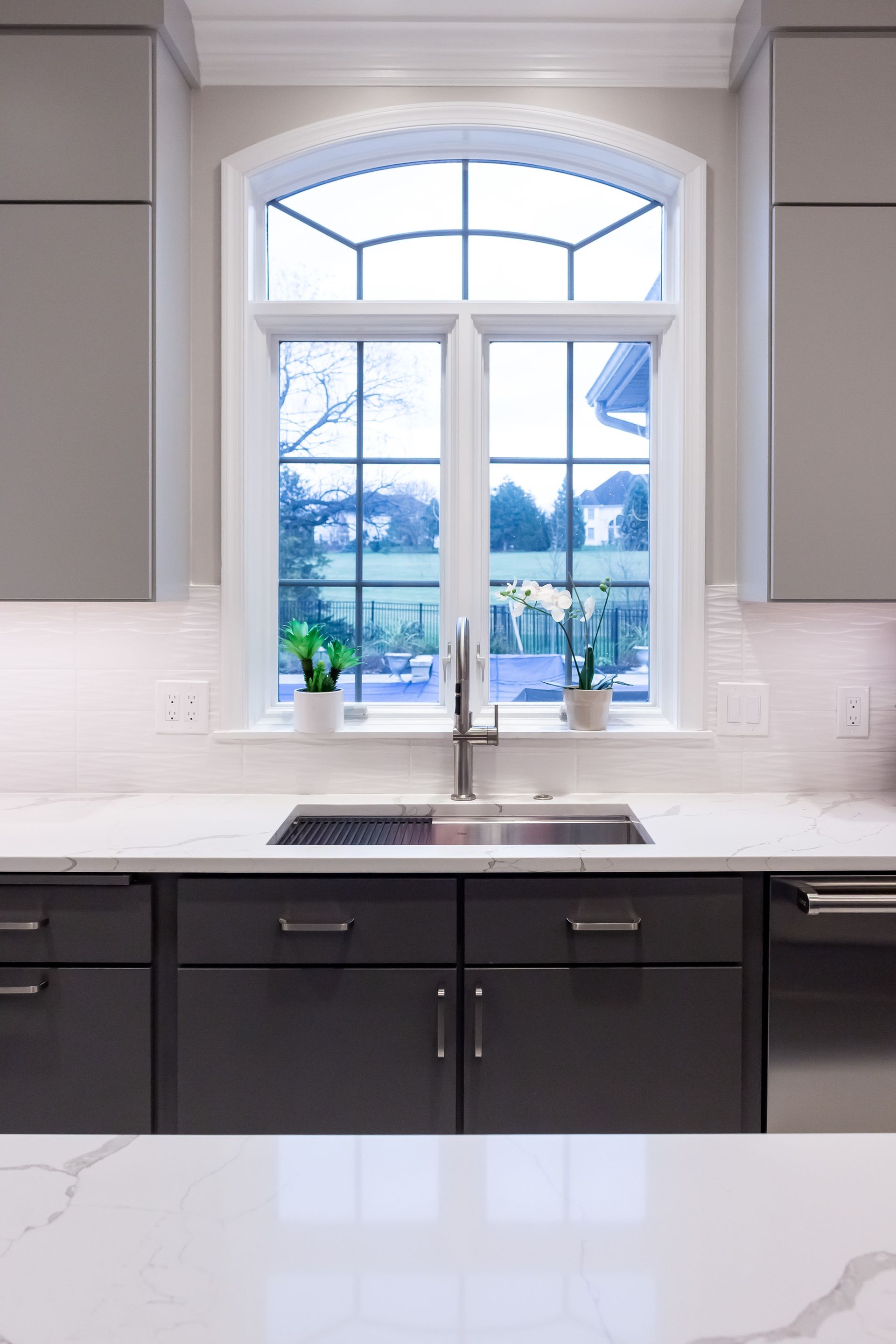 A kitchen with a sink , cabinets , and a window.