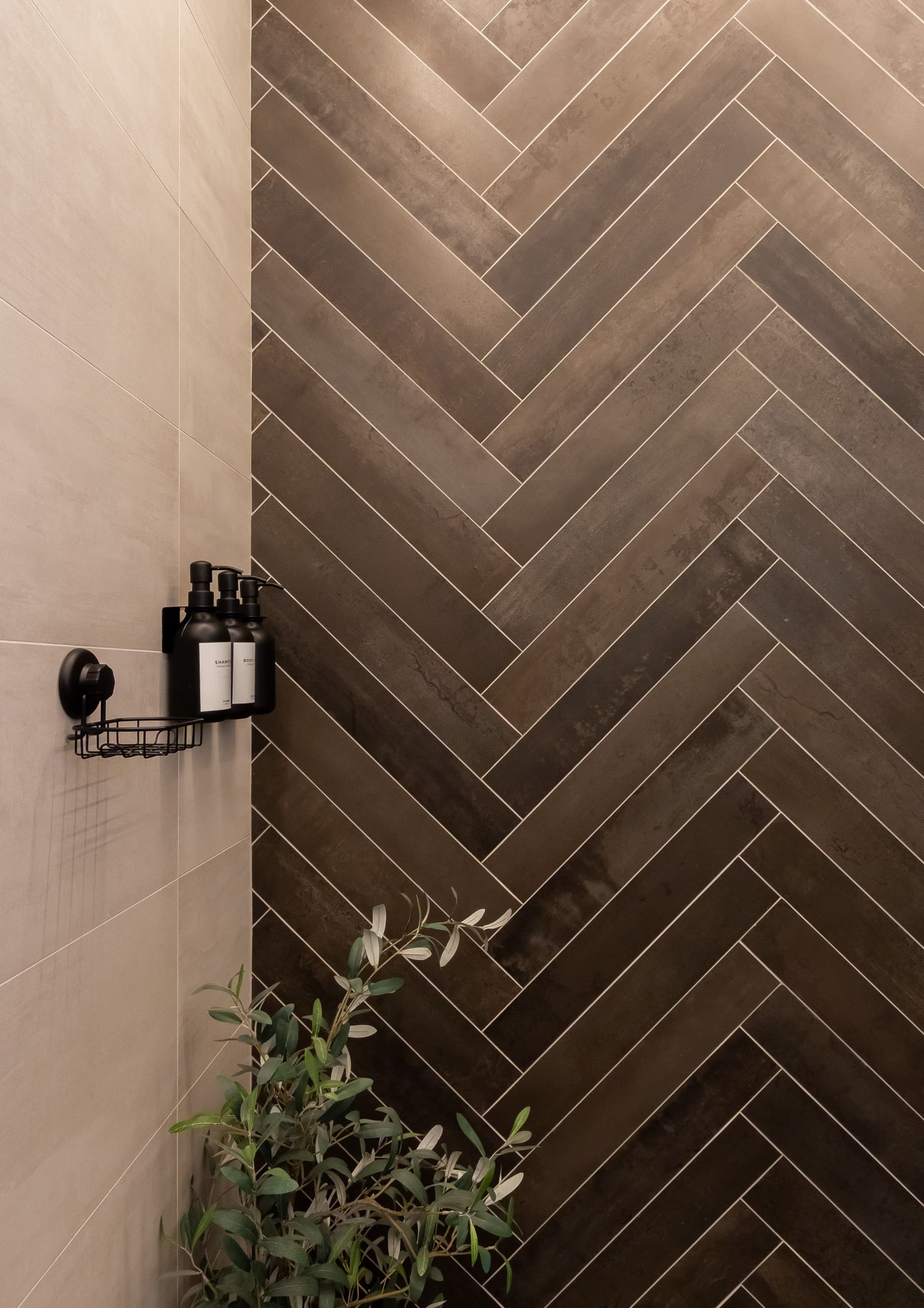 A bathroom with a herringbone pattern on the wall and a plant in the corner.