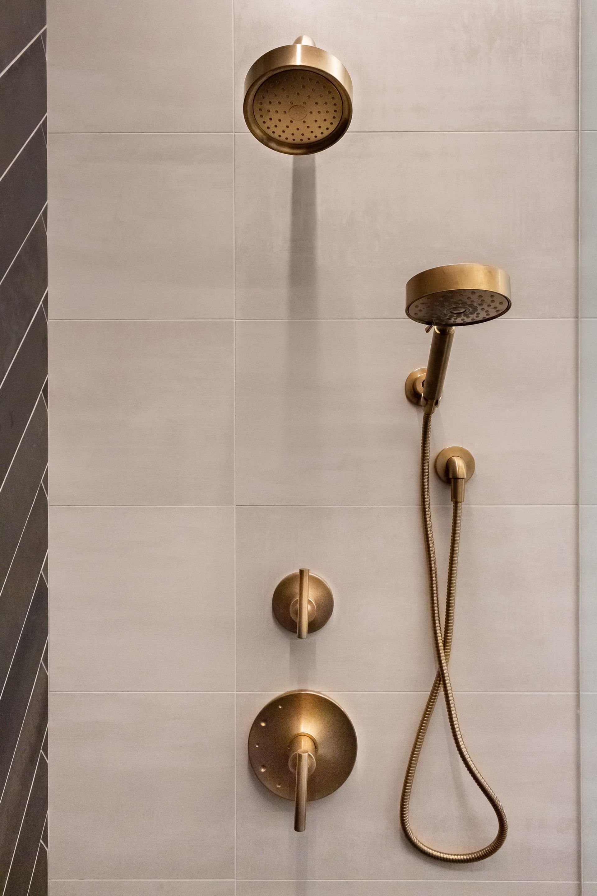 A shower head with a hose attached to it is on a tiled wall.