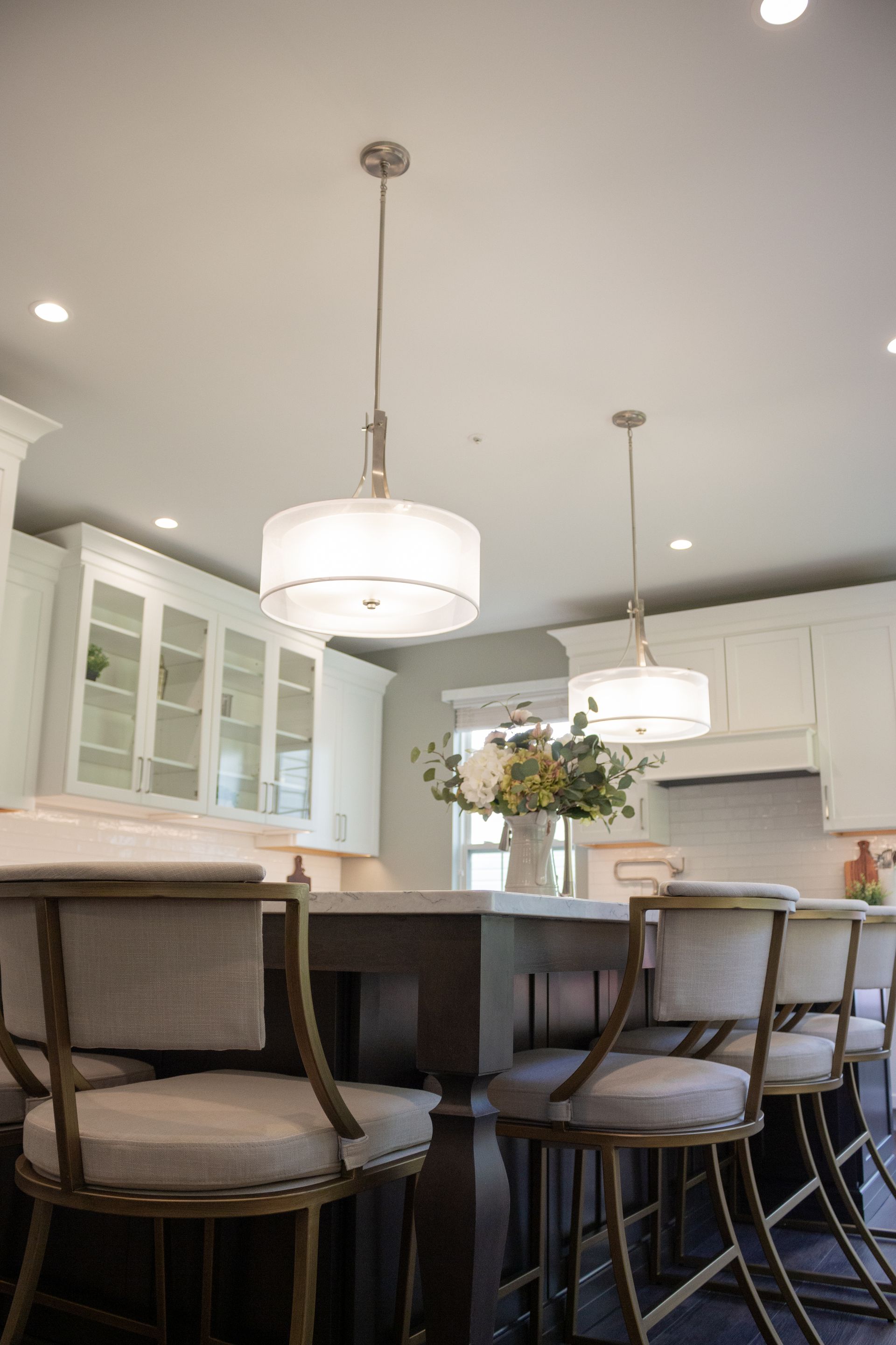 A kitchen with a table and chairs and a vase of flowers on the counter.