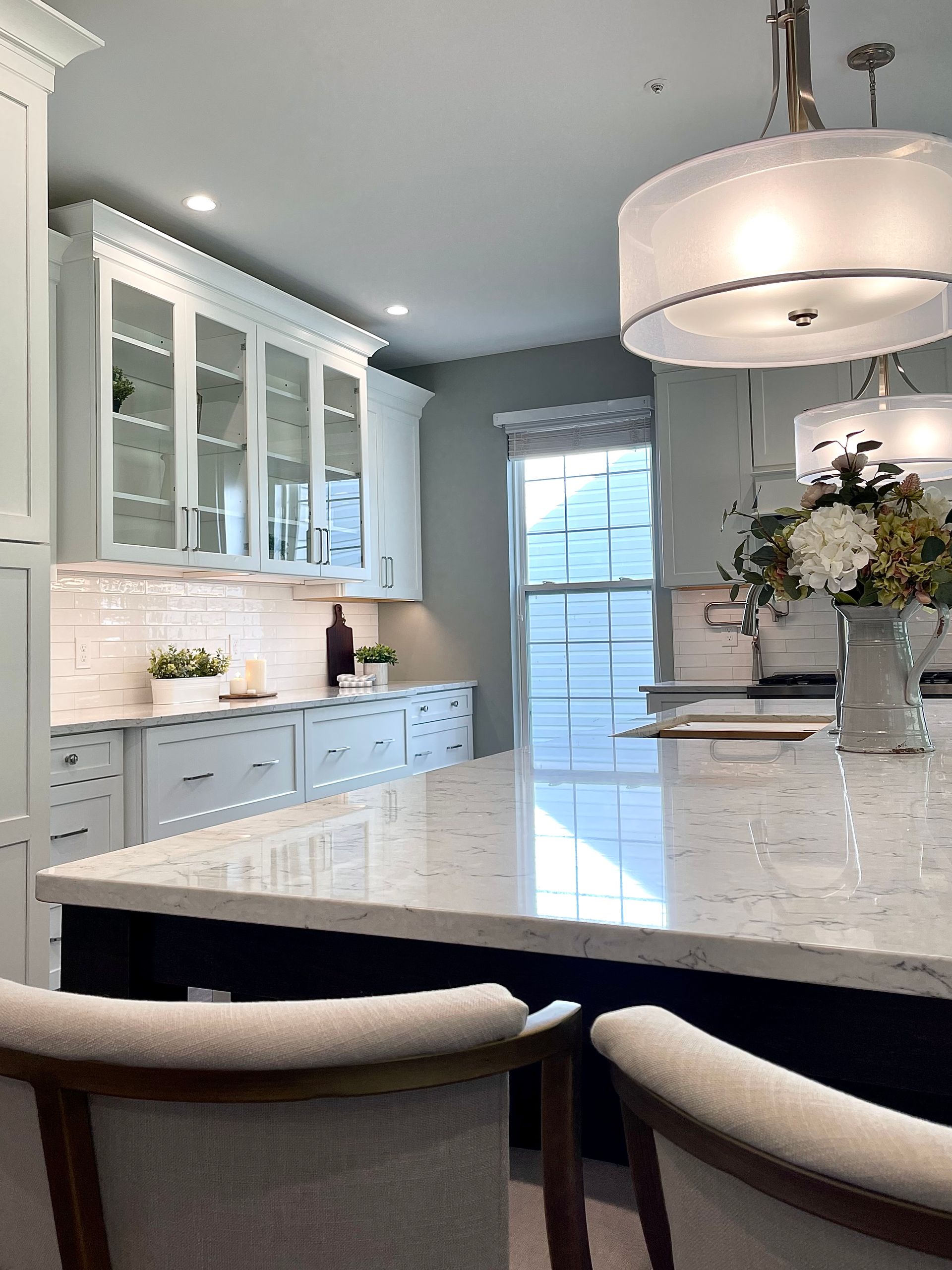 A kitchen with white cabinets and a marble counter top