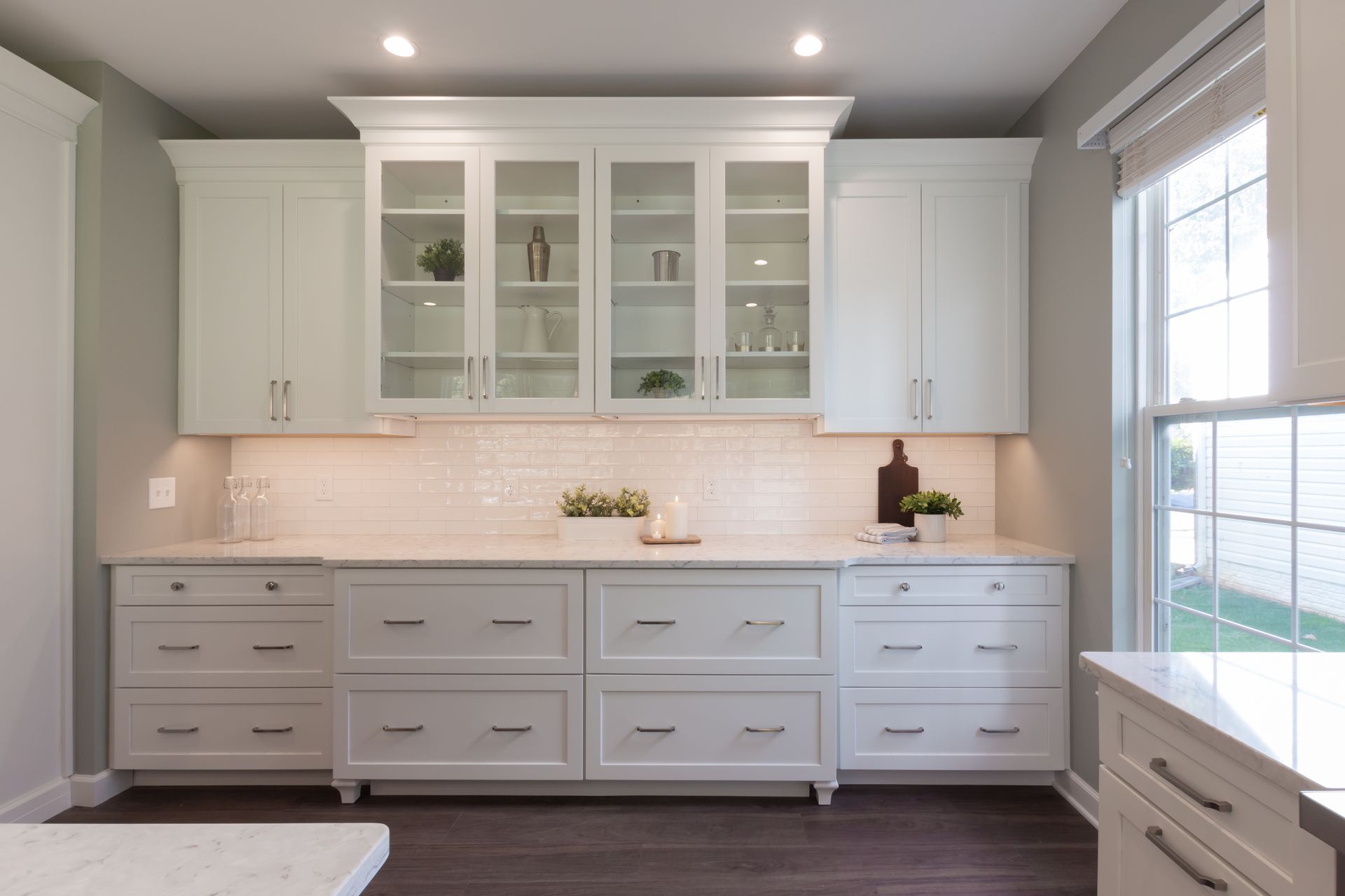 A kitchen with white cabinets , drawers , and a window.