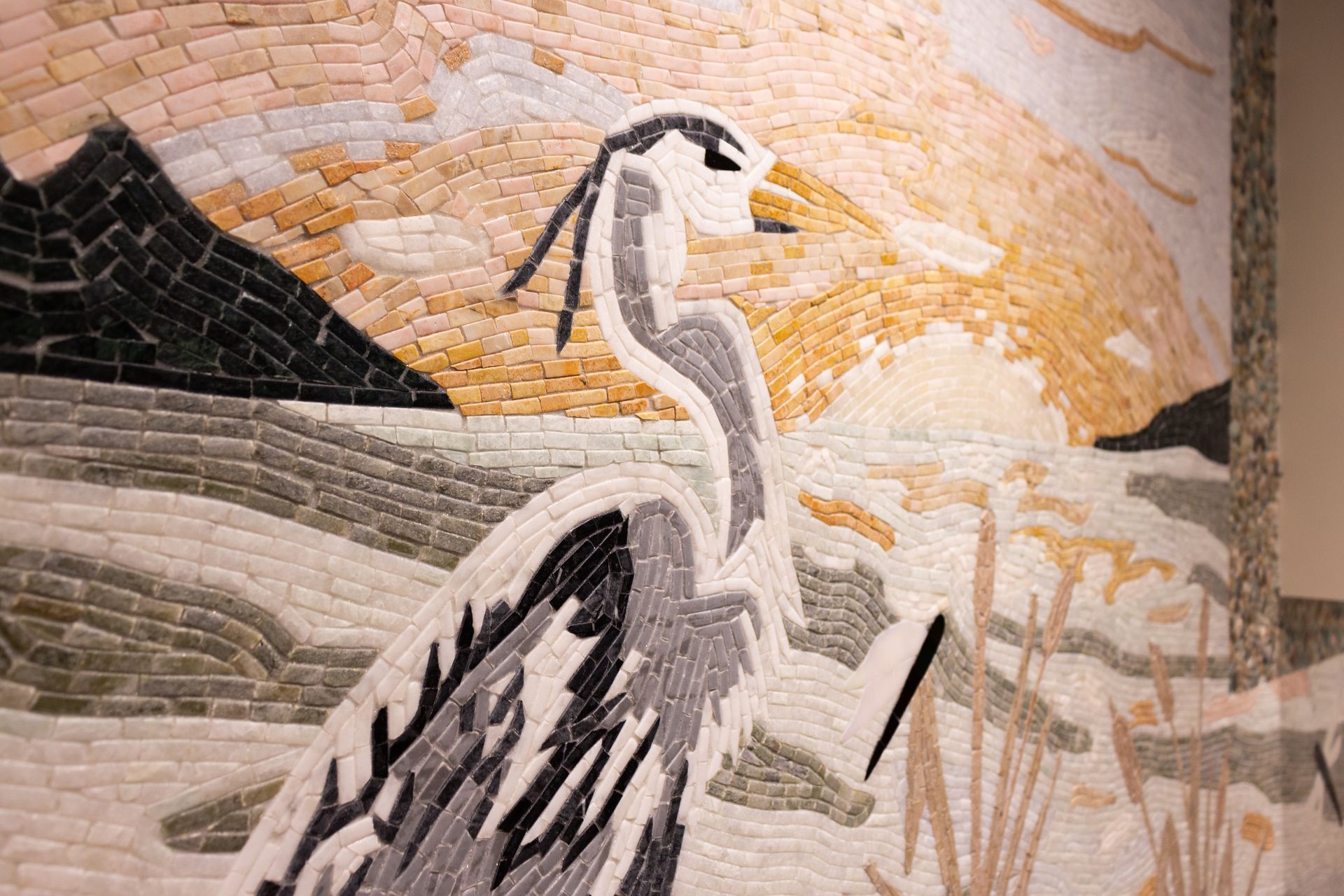 A close up of a mosaic of a bird on a wall.