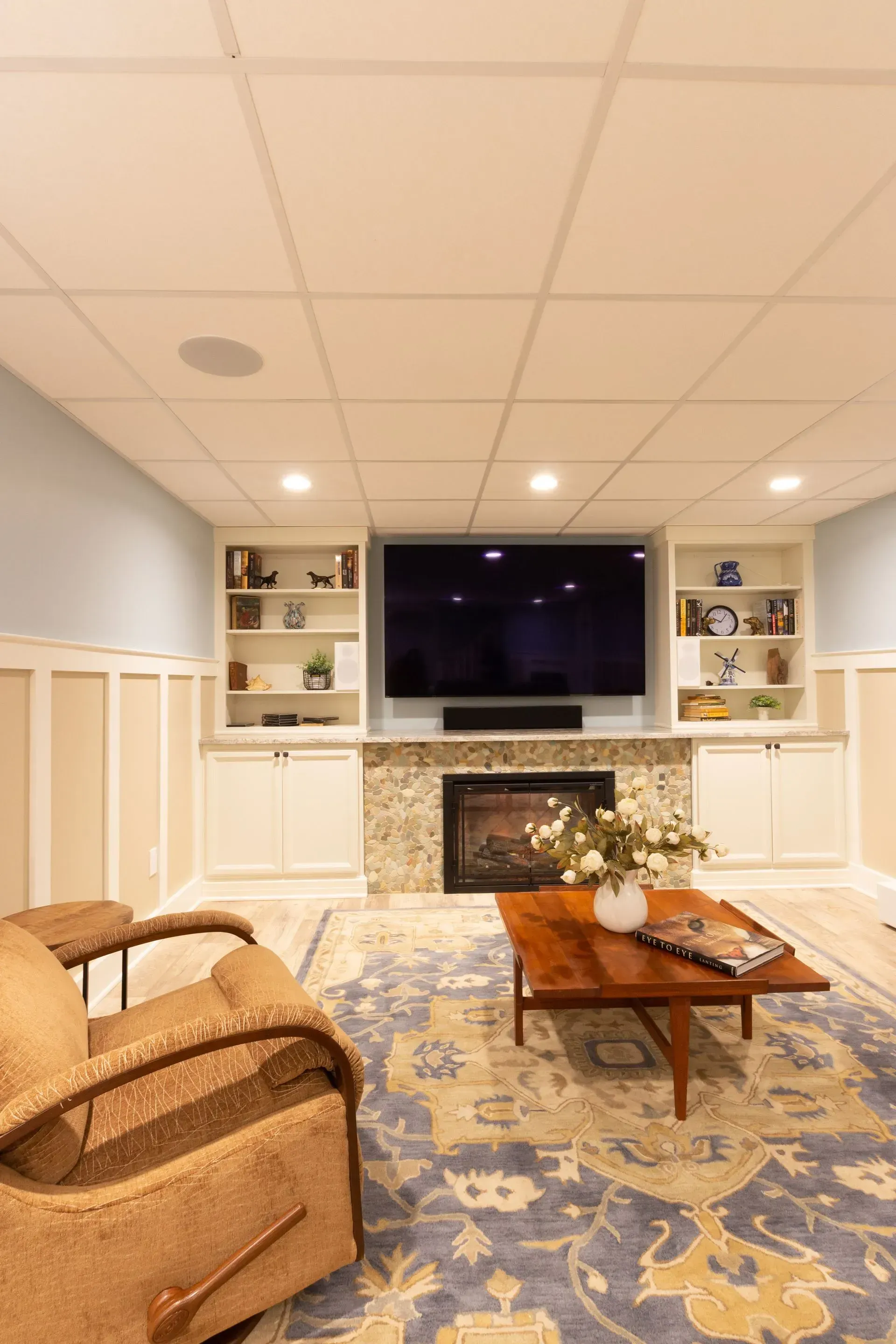 A living room with a fireplace , television , chair and coffee table.