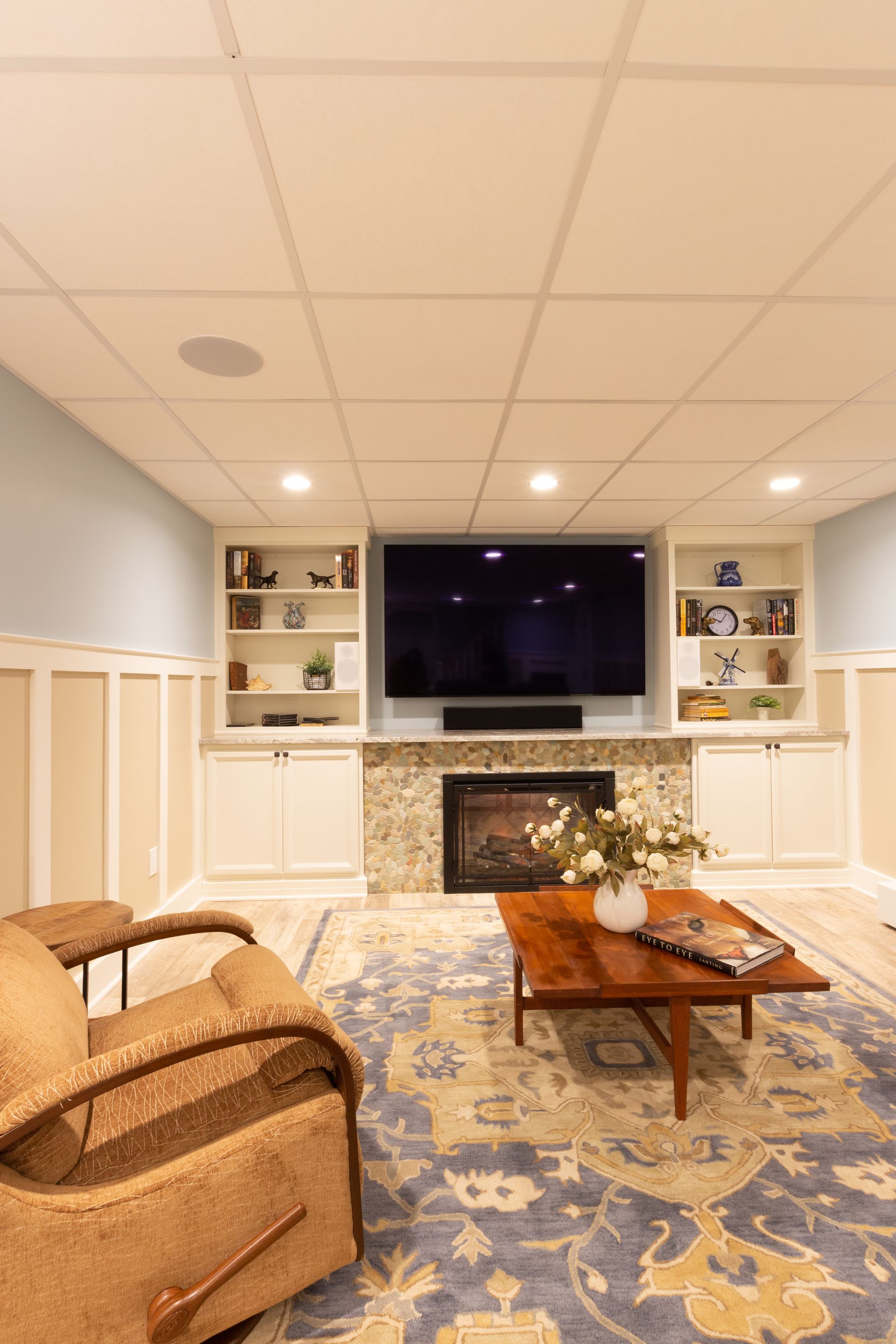 A living room with a fireplace , television , coffee table and chairs.